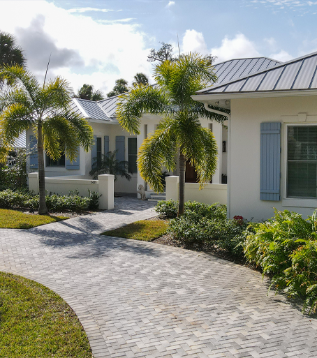 Circular paved driveway in front of white house with blue shutters